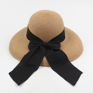 Top view of woven straw sun hat with black ribbon bow detail and fine texture