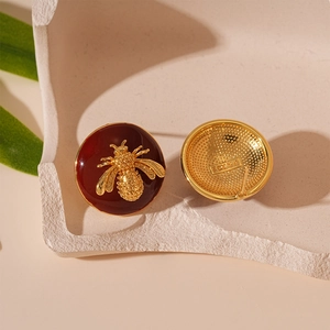 Macro detail of vintage gold bee earrings with red enamel and Paris engraving
