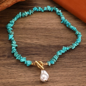 Detail of turquoise stone necklace with golden toggle clasp and baroque pearl pendant