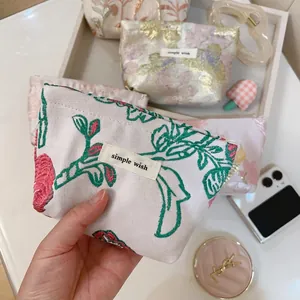 Close-up of floral embroidery on a mini canvas pouch with a secure zipper closure