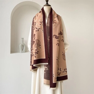 Détail de motifs floraux et franges sur une écharpe bordeaux et beige chic