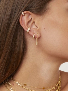 Close-up of gold paperclip earrings and layered necklaces with cubic zirconia inlay