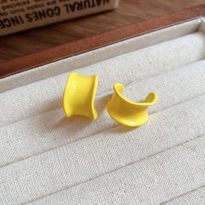 Macro shot of minimalist yellow C-shaped hoop earrings resting on a soft velvet jewelry box