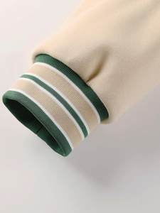 Vue détaillée du poignet en bord-côte vert foncé avec rayures blanches sur un blouson baseball