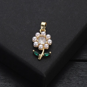 Détail macro d'un pendentif fleur dorée avec perles blanches et zircon sur socle noir