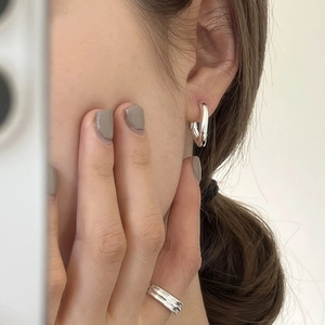 Detail of silver U-shaped hoop earrings and stacked ring set on a female model