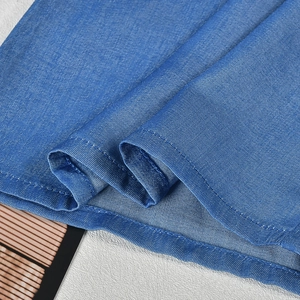 Detail view showing blue cotton fabric texture and precise double stitching on the hem
