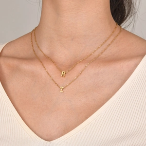 Detailed view of layered gold alphabet necklace with R and Z pendants on female neck