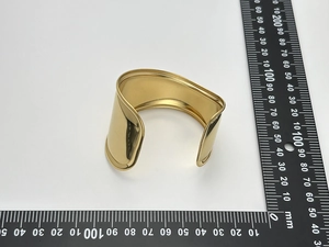 Detailed view of wide wave 18K gold-plated cuff bangle with measurement ruler