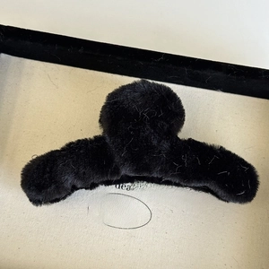 Detail shot of a black fuzzy plush hair claw clip resting in a premium jewelry display box