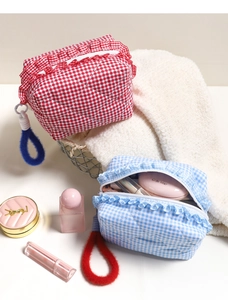 Close-up of quilted checkered cosmetic bags with ruffled edges and soft plush handles
