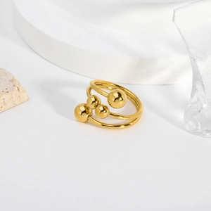 Anello multistrato in acciaio al titanio dorato lucido con quattro sfere su sfondo bianco