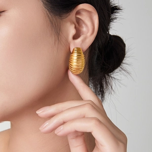 Golden oval hoop earrings with intricate spiral rope texture in a modern geometric design