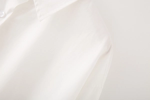 Close-up of a white cotton poplin shirt showing the collar, buttons and woven texture