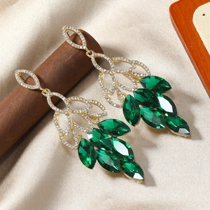 Détail de boucles d'oreilles dorées avec pierres marquises vertes et strass blancs