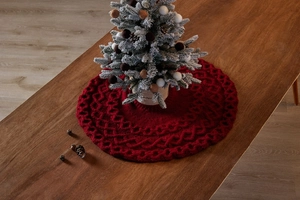 Gros plan sur le tapis de sapin de Noël rouge tricoté avec motif torsadé sur bois