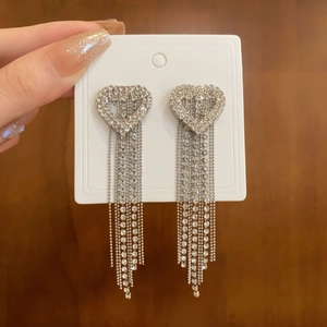 Macro view of silver heart tassel earrings with sparkling rhinestones and CD logo