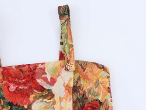 Detail of floral oil painting style brocade fabric with a golden hollow button on strap
