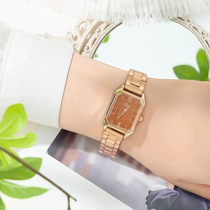 Dettaglio orologio rettangolare oro rosa con quadrante effetto legno e numeri romani