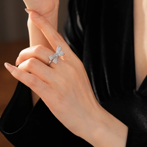 Close-up of zircon bow ring on model's finger with shimmering silver finish