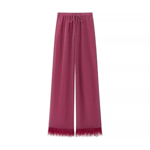 Détail du pantalon large fuchsia avec tissu scintillant et bordure en plumes élégante