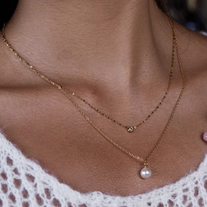 Gros plan d'un ensemble de colliers dorés avec perles et pendentifs en zircone sur modèle