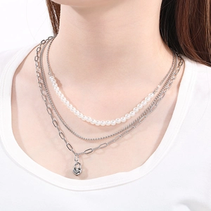 Close-up of triple-layered necklace featuring white pearls and heart lock pendant