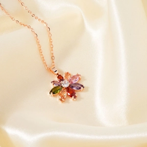 Close-up of a rose gold flower pendant necklace with colorful marquise stones on silk