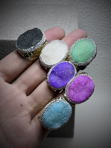 Detail of six adjustable bronze rings with oval druzy crystals in various colors
