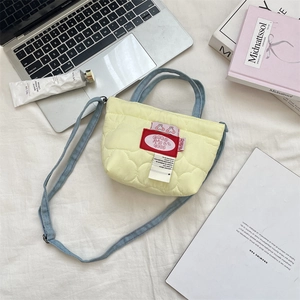Vue à plat d'un mini sac matelassé jaune avec des bretelles en denim bleu sur tissu blanc