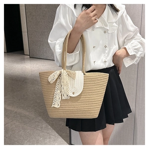 Detail of bohemian woven straw tote bag featuring white flap and elegant lace bow