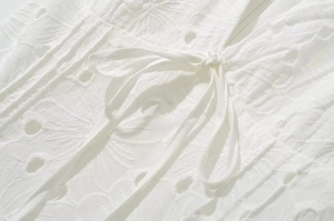 Vue macro de la broderie anglaise blanche et des détails de laçage sur le tissu