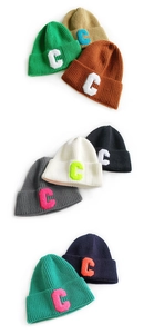 Close-up of assorted color knit beanies with embroidered C-letter towel patch detail