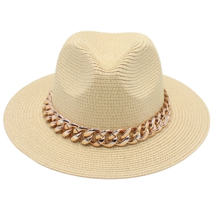 Détail du chapeau Panama en paille beige avec une grosse chaîne en or rose décorative