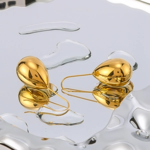 Polished gold water drop earrings made of stainless steel on reflective background