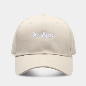 Detail der weißen SHARK-Stickerei und des Hai-Logos auf der beigen Baumwoll-Basecap