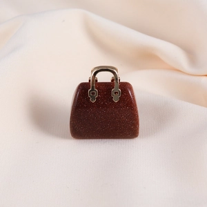 Macro shot of a reddish-brown crystal handbag pendant with a golden metal handle detail