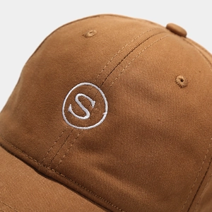 Close-up of white letter S embroidery on high-quality caramel cotton baseball cap fabric