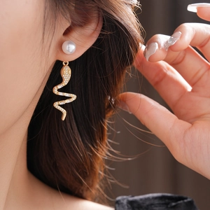 Detail of twisted gold snake earring with zircon crystals and pearl on model