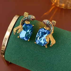 Macro shot of koi fish earrings with inlaid diamonds and large blue faceted gemstones