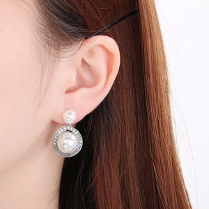 Gros plan de boucles d'oreilles vintage en argent avec perles et strass portées par un mannequin