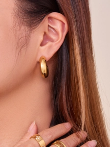 Close-up of polished gold-plated hollow C-shaped earrings with urban minimalist style