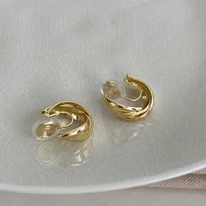 Vue détaillée de boucles d'oreilles géométriques dorées torsadées sur plateau
