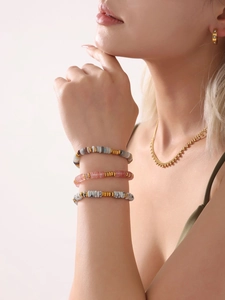 Close-up of stacked beaded bracelets with natural stones and 18K gold-plated beads on wrist
