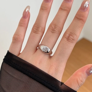Detail shot of a wide silver band ring featuring a sparkling heart-shaped zircon stone