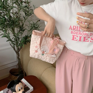 Detailed view of pink quilted tote bag with floral embroidery and fluffy flower charm