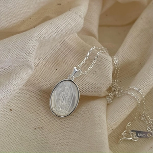 Macro shot of S925 sterling silver Virgin Mary shell necklace with religious engraving
