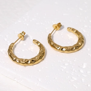 Detailed macro view of 18K gold plated stainless steel C-hoop earrings with hammered texture