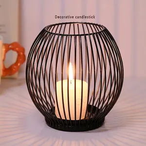 Nordic black iron hollow spherical candle holder with warm radial shadows on the table
