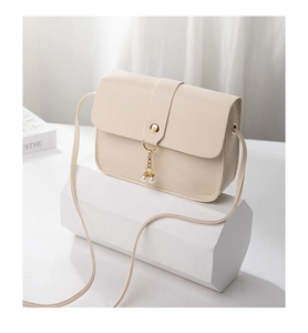 Close-up of cream crossbody bag featuring gold buckle and elegant pearl charm detail